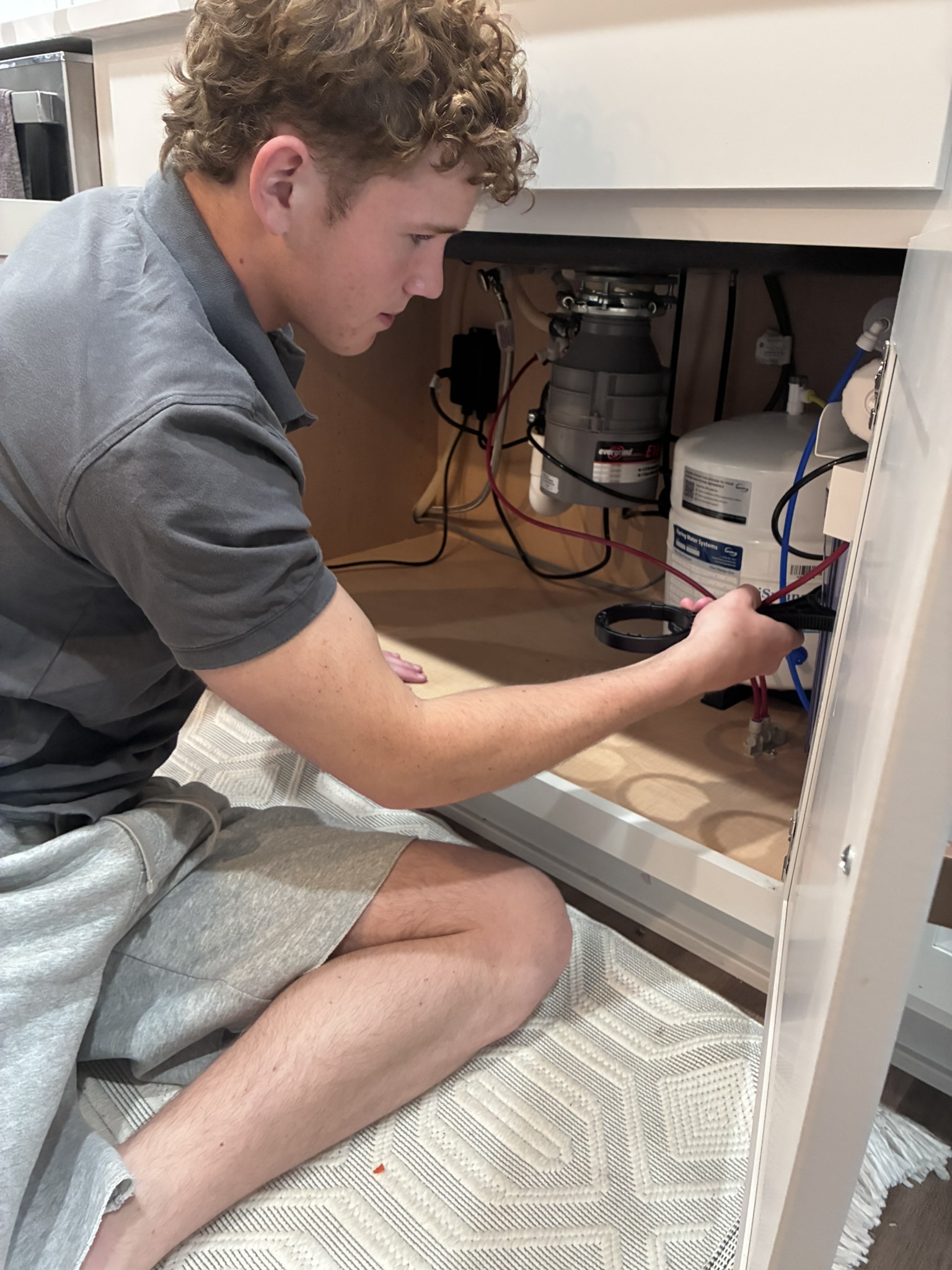 PrimeFlow technician connecting RO water system under kitchen sink Des Moines